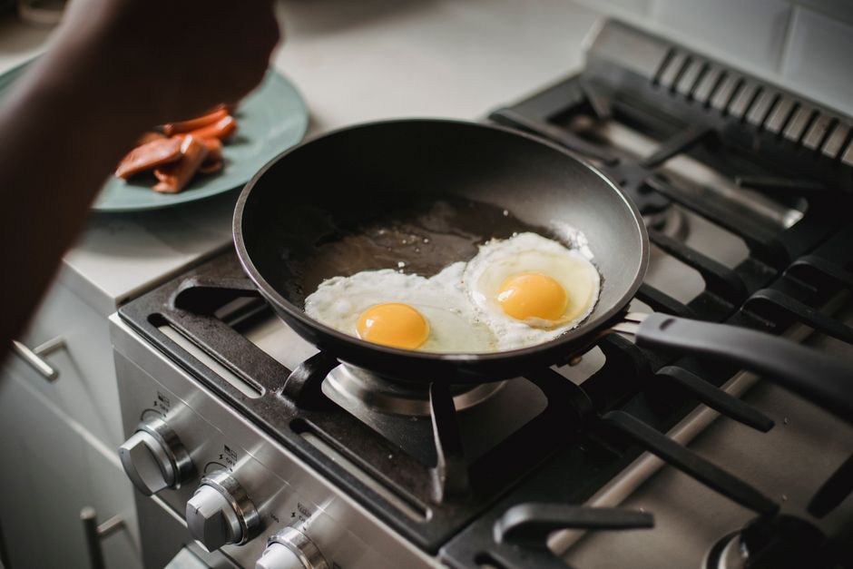 Acercamiento de dos huevos fritos cocinándose en una sartén en una cocina moderna.