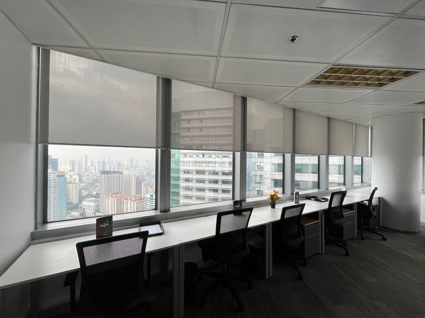 Interior de oficina elegante y moderno con escritorio y sillas con vista al paisaje urbano.