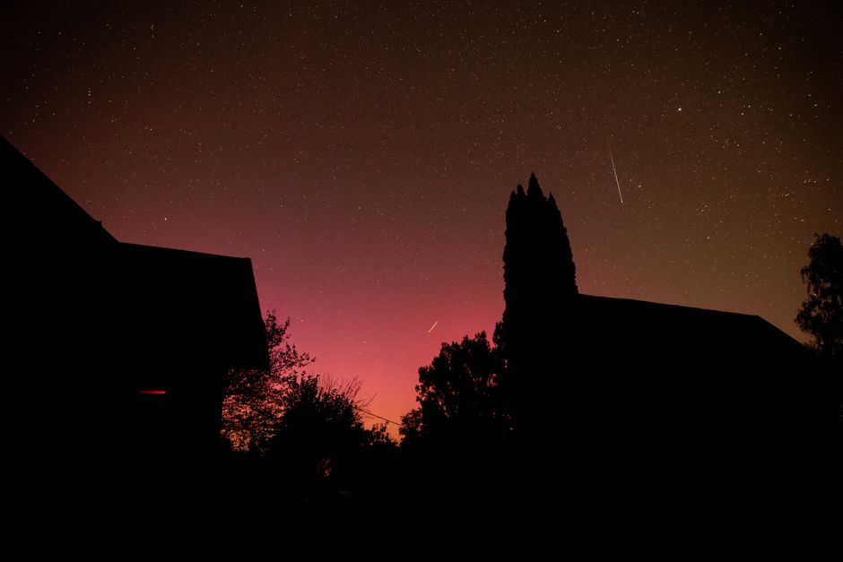 Impresionante vista de un cielo nocturno estrellado con siluetas de edificios y árboles.