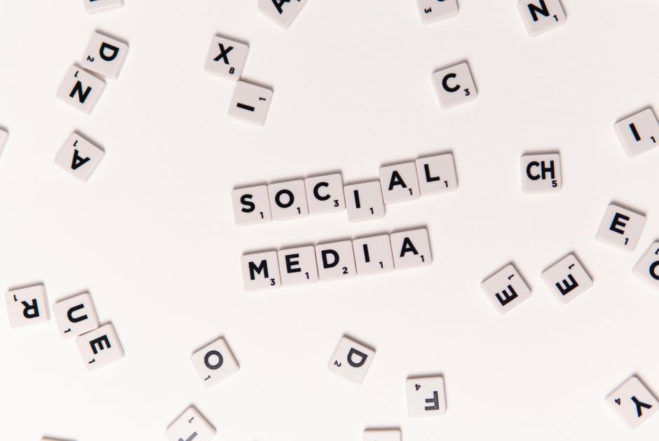 Vista desde arriba de fichas de letras que deletrean Redes Sociales con fichas blancas esparcidas sobre una superficie.