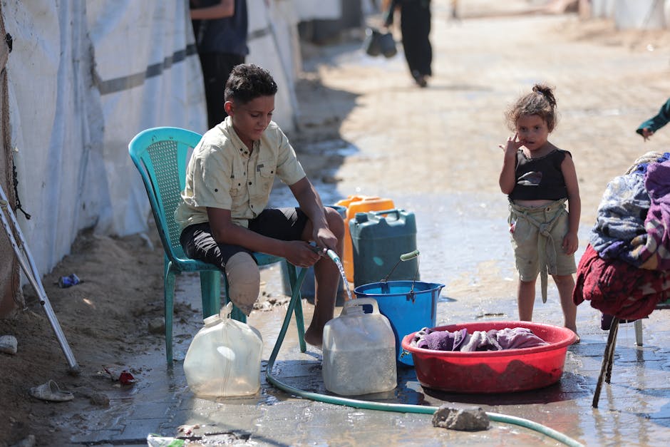 Niño recogiendo agua en un campo de refugiados, poniendo de relieve los desafíos diarios.