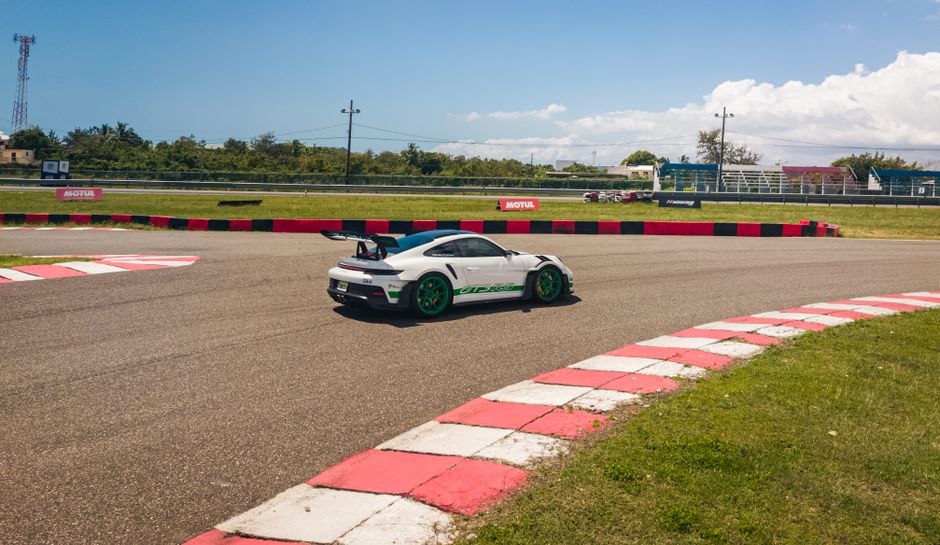 Un coche deportivo de alto rendimiento maniobra en una curva de la pista bajo un cielo brillante y despejado.