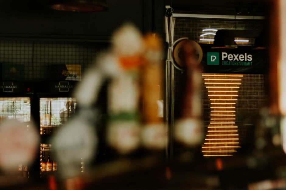 Ambiente cálido de un pub con enfoque difuso, mostrando un cartel de la Cumbre de Creadores de Pexels.
