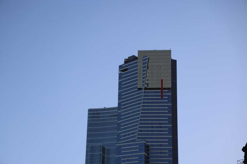 Un rascacielos moderno y alto con un diseño único, recortado contra un cielo azul despejado.