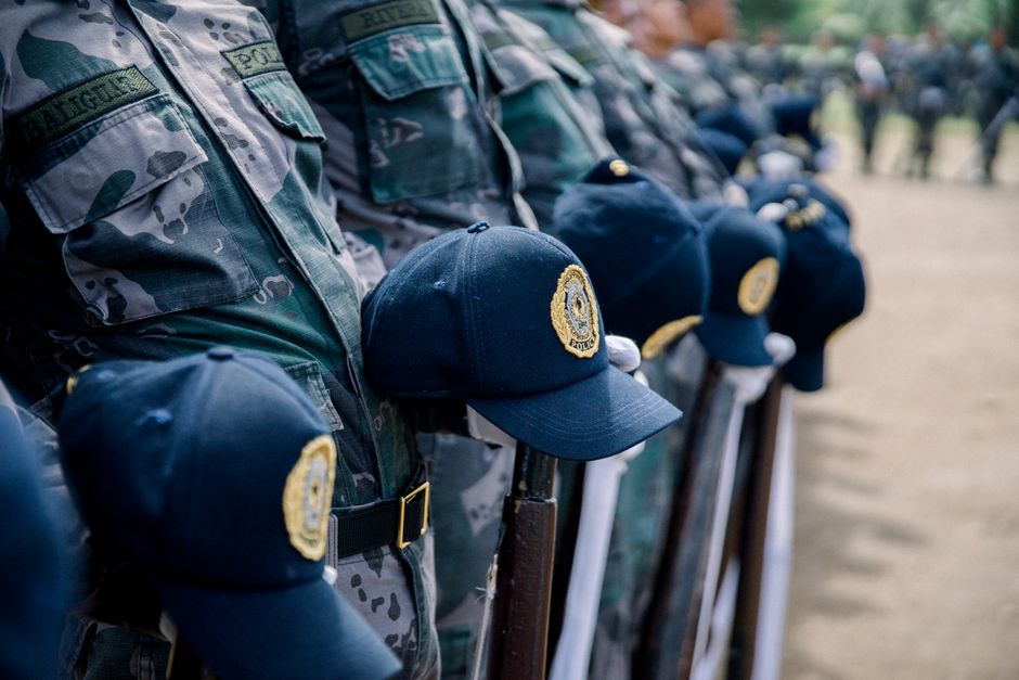 Primer plano de oficiales de policía uniformados formados con gorras en exhibición al aire libre.