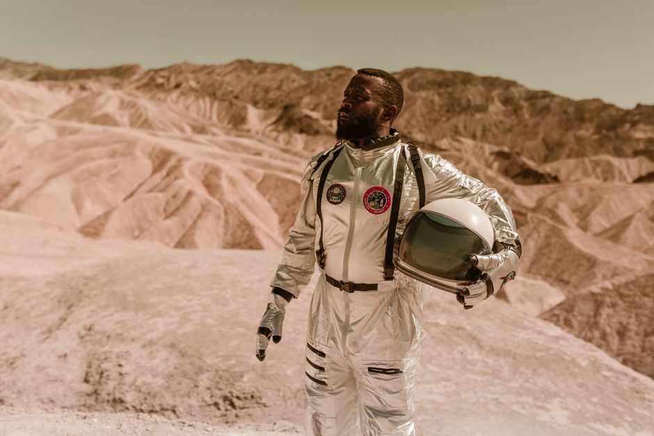Un hombre en un traje espacial explora un desierto rocoso, que se asemeja a la superficie de un planeta alienígena.