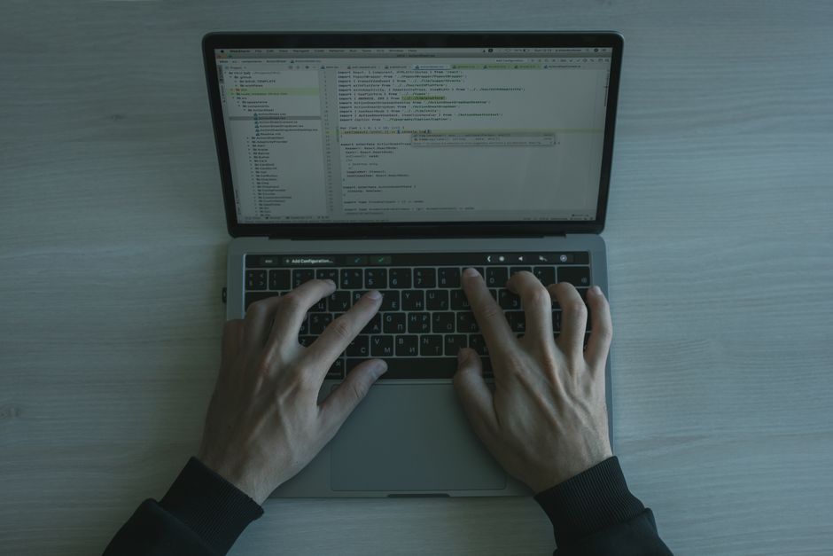 Vista en primer plano de un programador codificando en un laptop, mostrando el desarrollo de software moderno.