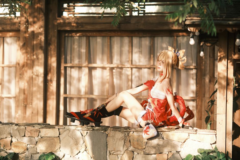 Una mujer con un traje de cosplay detallado se sienta elegantemente al aire libre bajo la cálida luz del sol.