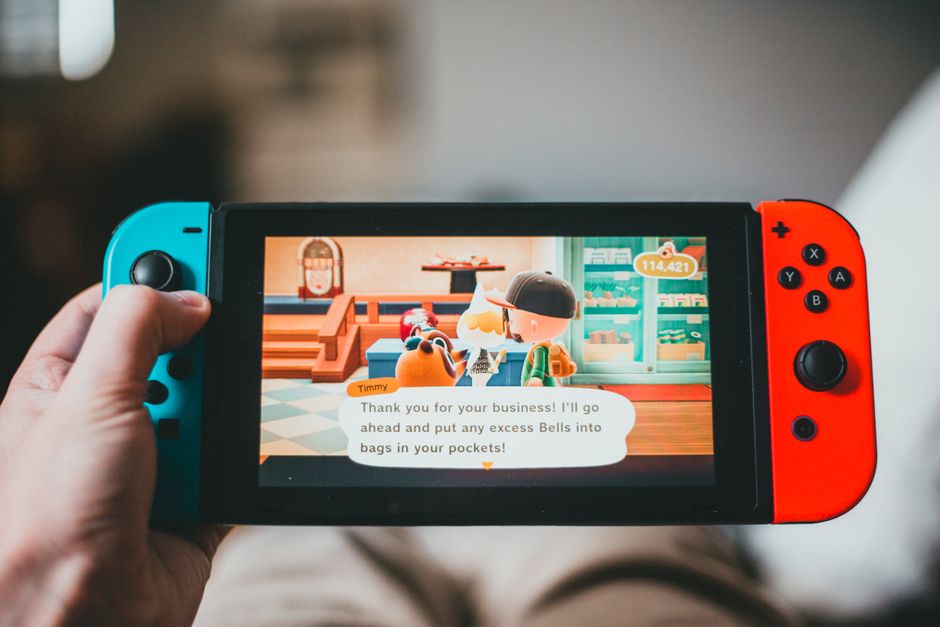 Primer plano de una persona disfrutando de un colorido videojuego en una consola portátil en interiores.