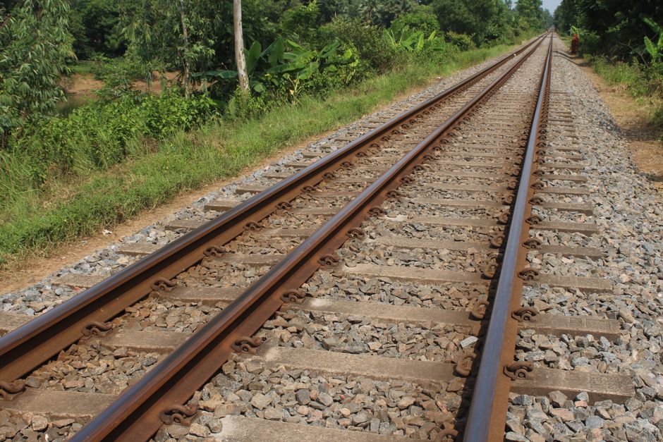 Vista panorámica de las vías del tren que se extienden a través de una exuberante vegetación bajo un cielo despejado.