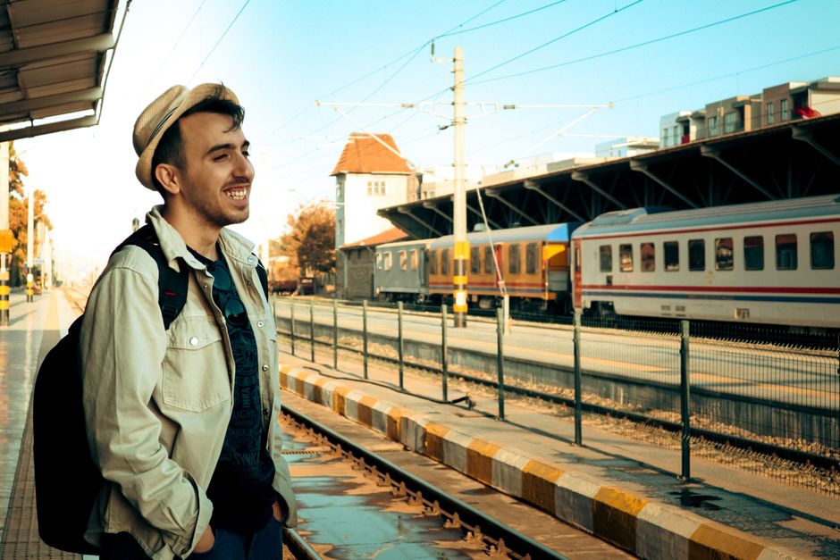 Un viajero alegre en la estación de tren de Balıkesir, Turquía, disfrutando de un día soleado.