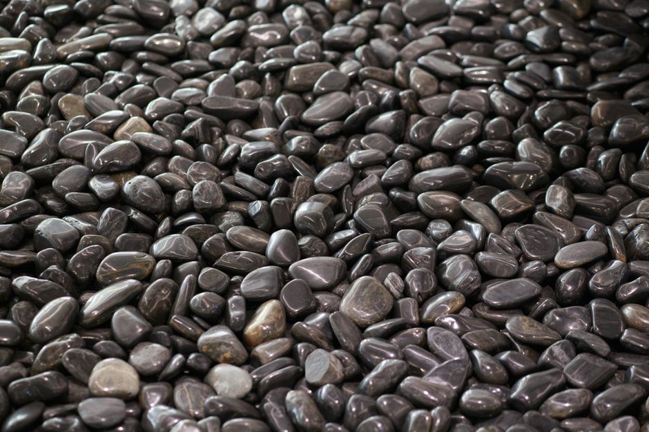 Imagen de alta resolución de piedras de río negras pulidas, ideales para ambientes de spa y relajación.
