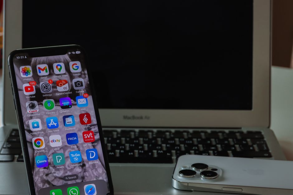 Primer plano de un teléfono inteligente y una computadora portátil en un escritorio, mostrando productividad y conectividad.