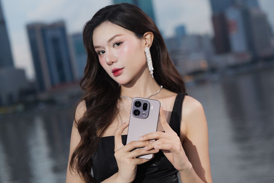 Mujer elegante con smartphone posando afuera frente a un fondo urbano.