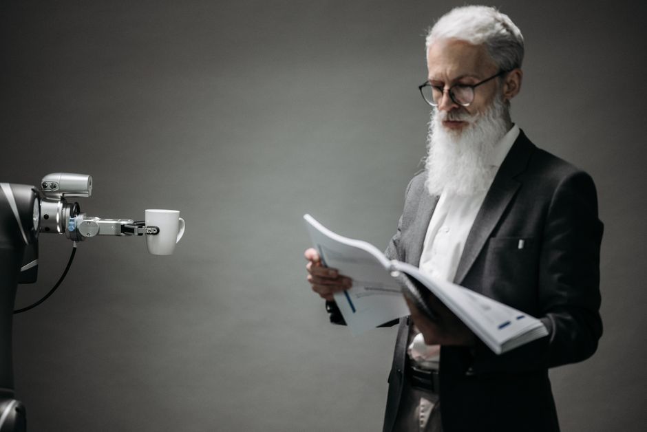 Un brazo robótico asiste a un profesional con un libro y café en una oficina moderna. La tecnología se encuentra con la innovación.