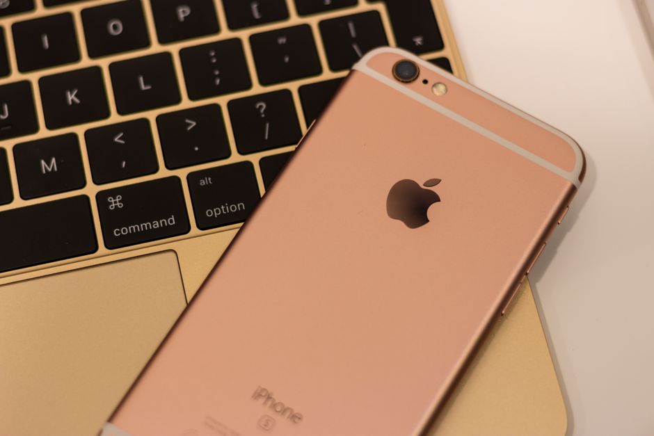Primer plano de un iPhone 6s rosa dorado colocado sobre el teclado de un MacBook, mostrando un diseño elegante y tecnología moderna.