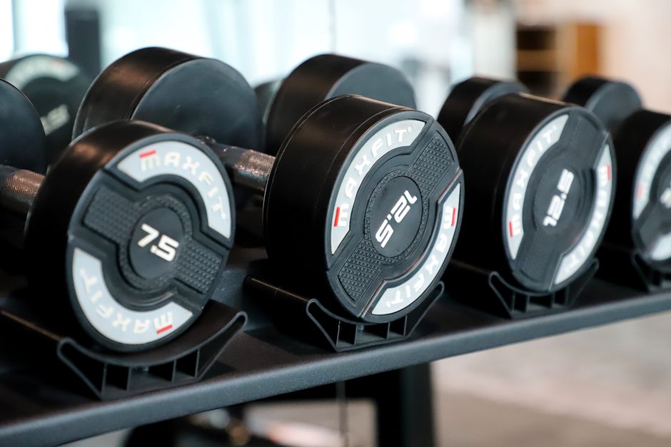Imagen de alta calidad de varias mancuernas cuidadosamente colocadas en un estante en un gimnasio contemporáneo.