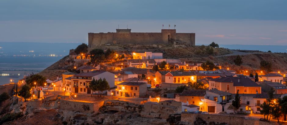 El castillo de Chinchilla al anochecer, con vistas a un pueblo medieval iluminado en Albacete, España.