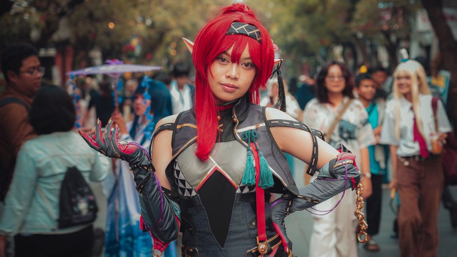 Persona en un detallado traje de cosplay posando en un evento al aire libre, entorno vibrante y dinámico.