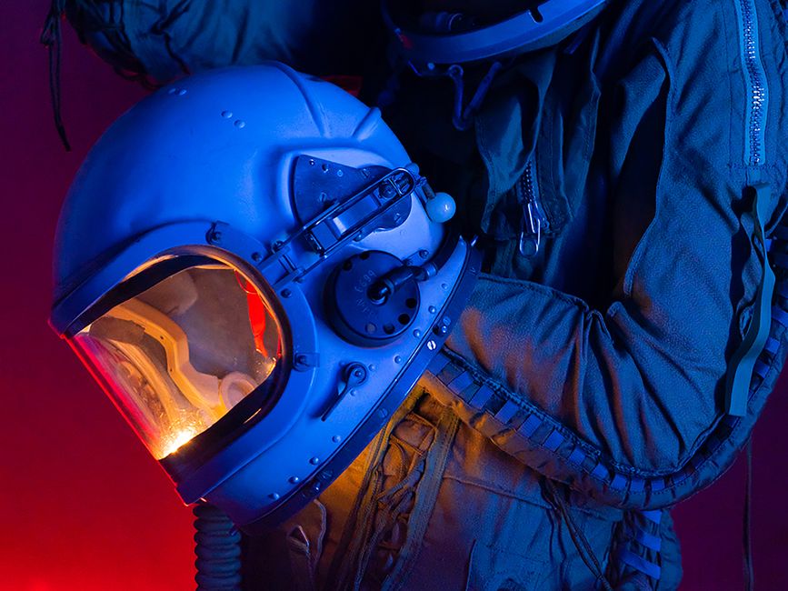 Una persona en un traje espacial sosteniendo un casco de astronauta con iluminación colorida.