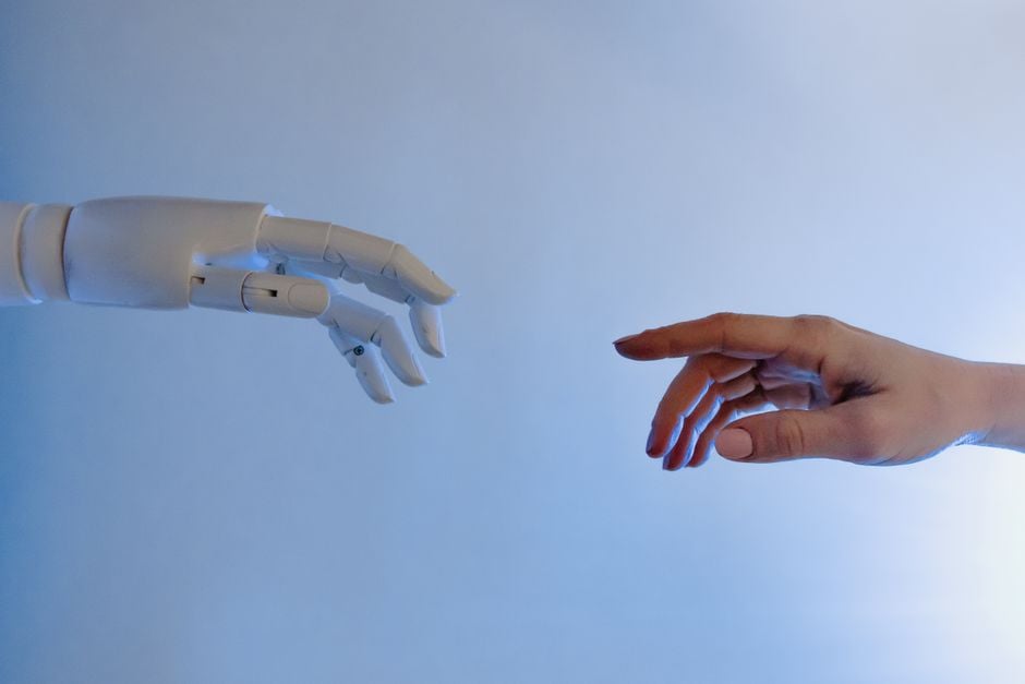Una mano humana extendiéndose hacia una mano robótica que simboliza la tecnología y la conexión.
