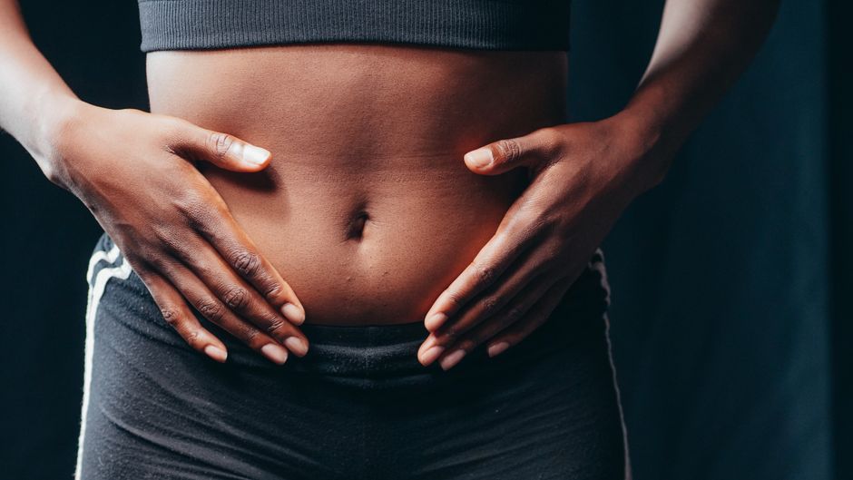 Imagen en primer plano de manos en el abdomen que significa bienestar, conciencia corporal o chequeo de salud.