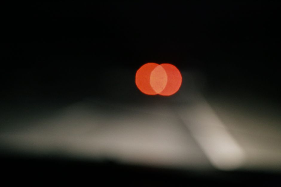 Una toma borrosa de las luces traseras de vehículos creando un efecto bokeh en una escena nocturna de carretera oscura.