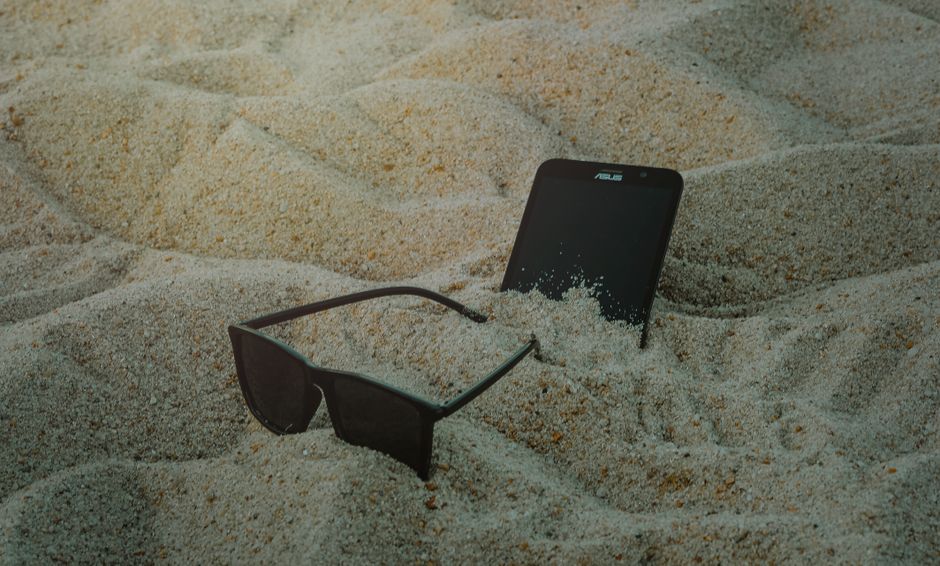 Foto De Teléfono Y Gafas De Sol Sobre Arena.