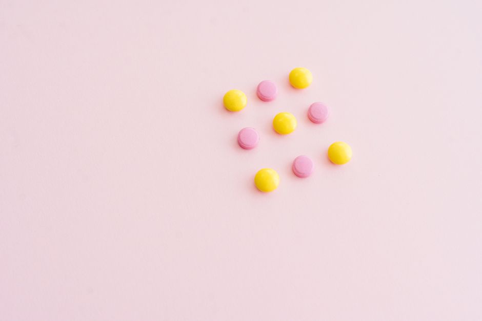 Píldoras vibrantes amarillas y rosas dispuestas sobre una superficie rosa, ofreciendo amplio espacio para texto. Perfecto para temas de salud.