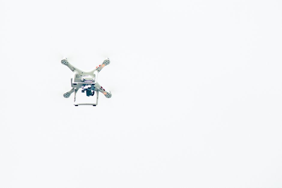 Una captura minimalista de un dron volando contra un cielo despejado.