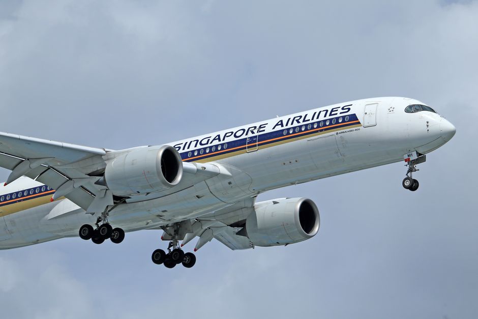 Una vista en primer plano de un avión de Singapore Airlines volando contra un cielo nublado.