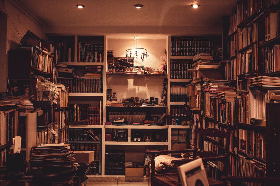 Una biblioteca en casa, iluminada cálidamente, llena de una diversa colección de libros y con un ambiente acogedor.