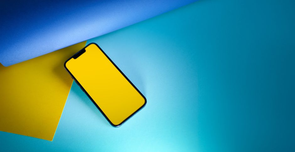 Smartphone estilizado con pantalla amarilla sobre papel azul y amarillo, ideal para conceptos de tecnología y diseño.