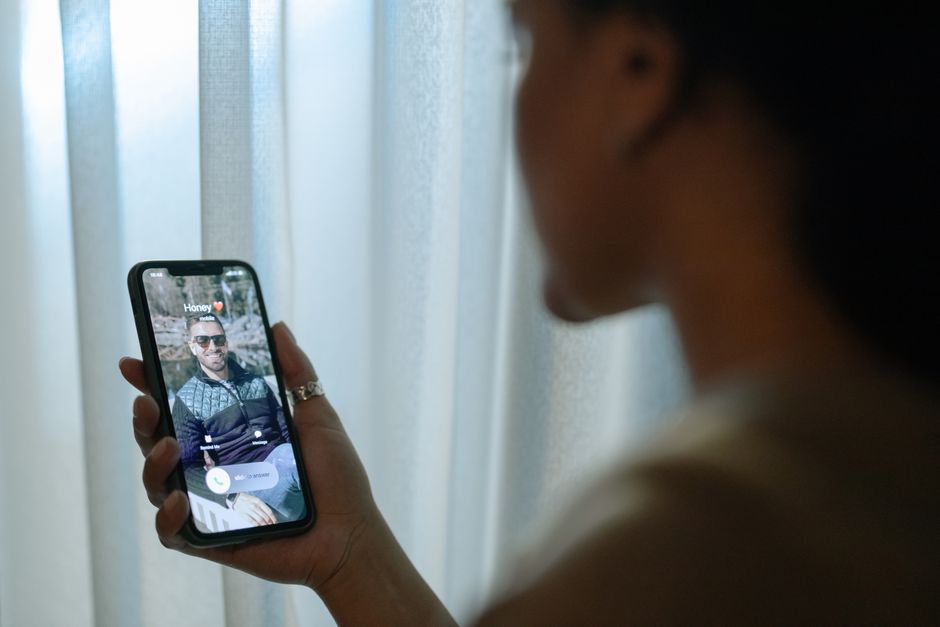 Una mujer sostiene un smartphone que muestra una llamada entrante de 'Cariño' con un fondo desenfocado.