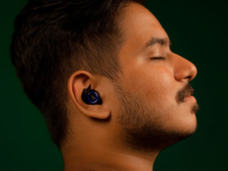 Acercamiento de un hombre escuchando música con auriculares, ojos cerrados, expresión serena.