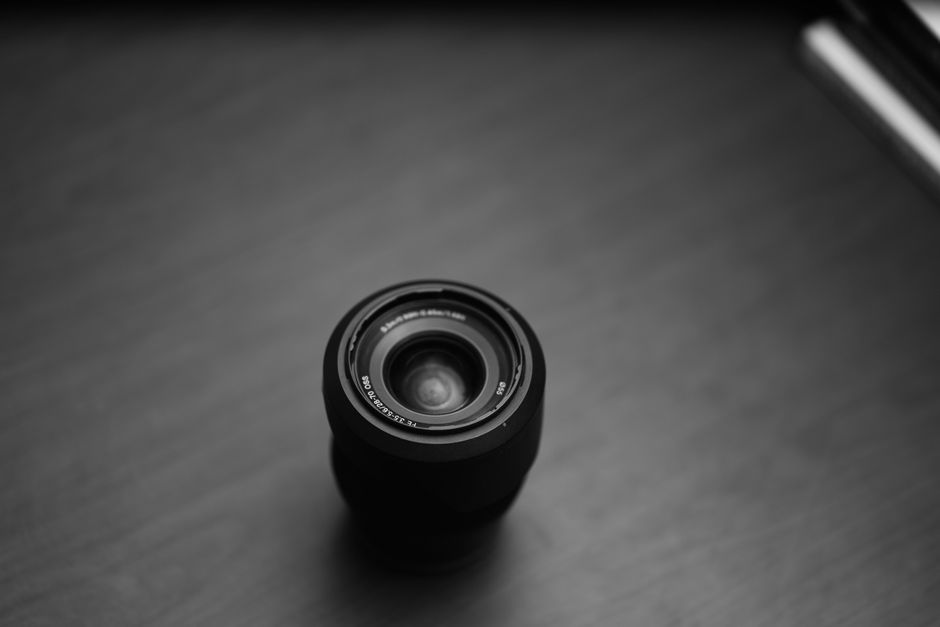 Vista superior de un objetivo de cámara en un entorno minimalista en blanco y negro, que muestra los elementos esenciales de la fotografía.