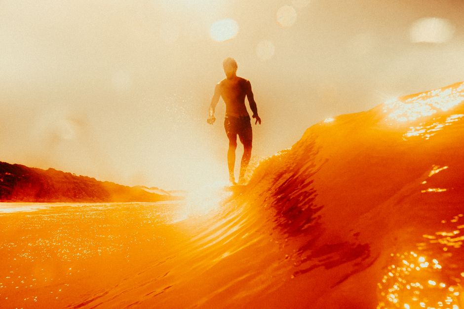 Un surfista monta una ola vibrante bajo un atardecer naranja en Pipa, Brasil, capturando la esencia de la aventura.