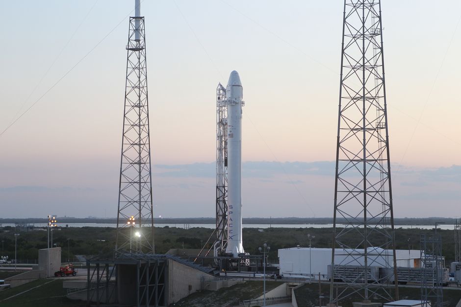 Nave espacial en la plataforma de lanzamiento durante el atardecer, rodeada de torres en preparación para el despegue.
