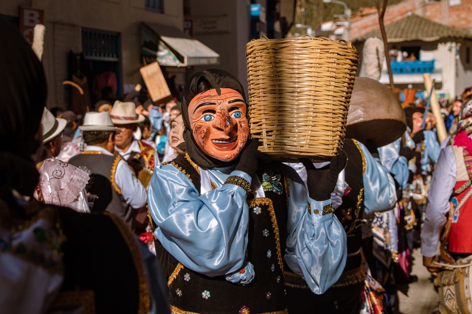 Celebración colorida en Paucartambo, Perú, con danzantes enmascarados tradicionales durante un festival callejero.