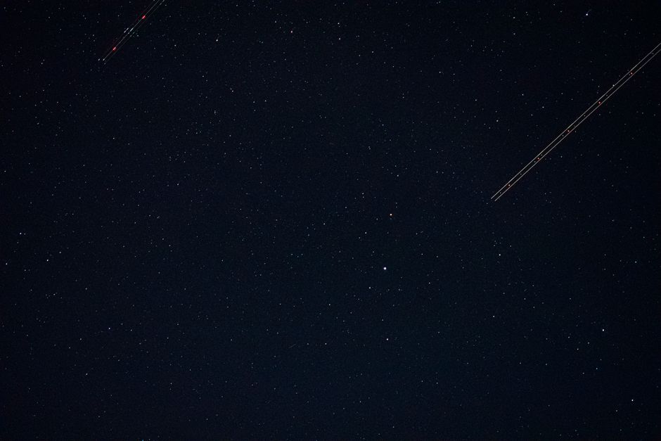 Una vista cautivadora de un cielo nocturno lleno de estrellas con trayectorias de luz distintas.