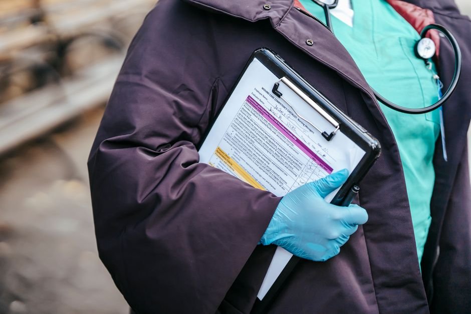 Personal médico sostiene una carpeta con documentos y lleva un estetoscopio.