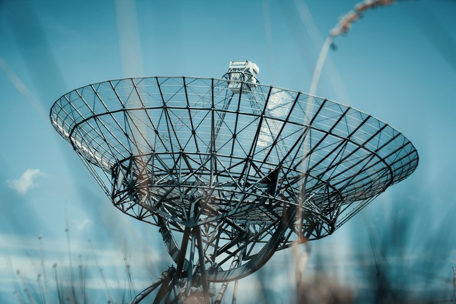 Una gran torre de plato satelital contra un cielo azul claro, simbolizando la tecnología de comunicación.