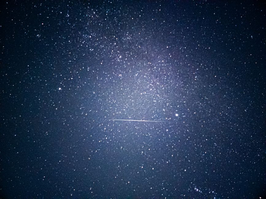 Contempla el cielo nocturno lleno de estrellas con una brillante estrella fugaz.