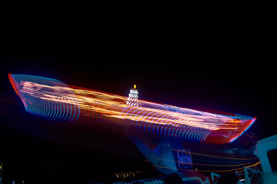 Exposición prolongada dinámica de una atracción de feria en movimiento con luces de neón vibrantes en Montevideo, Uruguay.