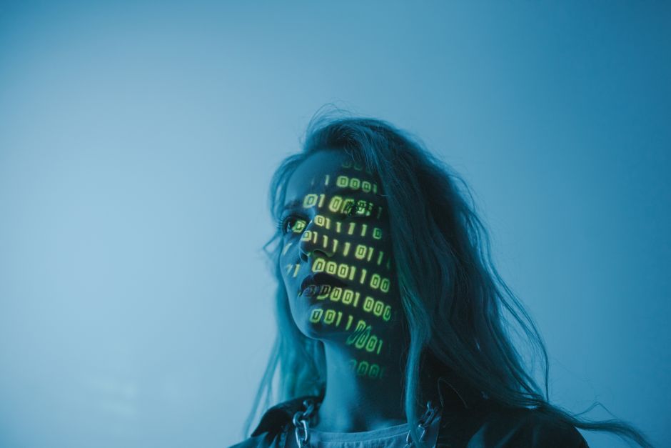 Una mujer con código binario proyectado en su rostro, simbolizando la tecnología.
