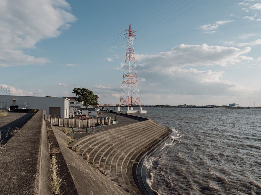 Líneas de alta tensión junto al mar en Toyohashi, Japón, con olas rompiendo en los escalones.