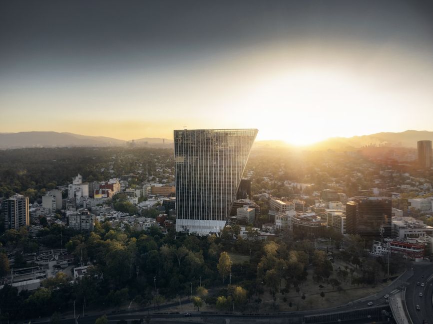 Vista aérea del horizonte de Ciudad de México al atardecer, con un edificio moderno distintivo.