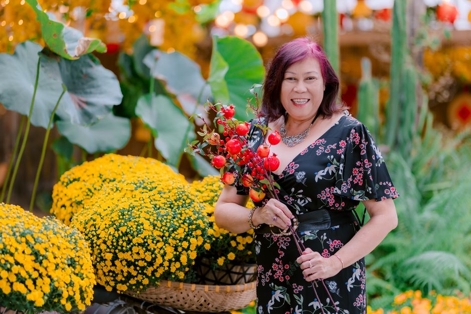 Mujer sonriente sosteniendo bayas de otoño entre flores amarillas vibrantes, irradiando calidez estacional.