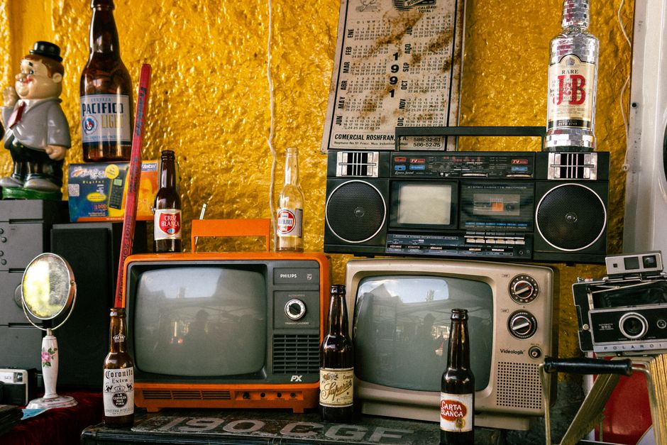 Una disposición nostálgica de electrónica vintage y botellas en un entorno retro.