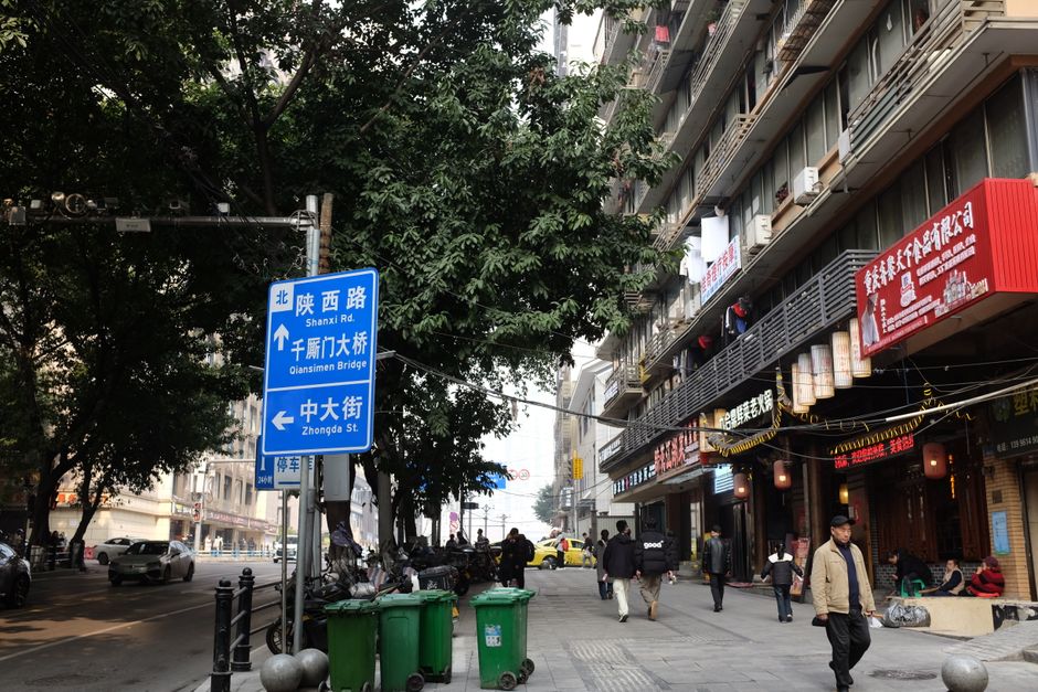 Una calle concurrida en China con señales, peatones y diversas tiendas.